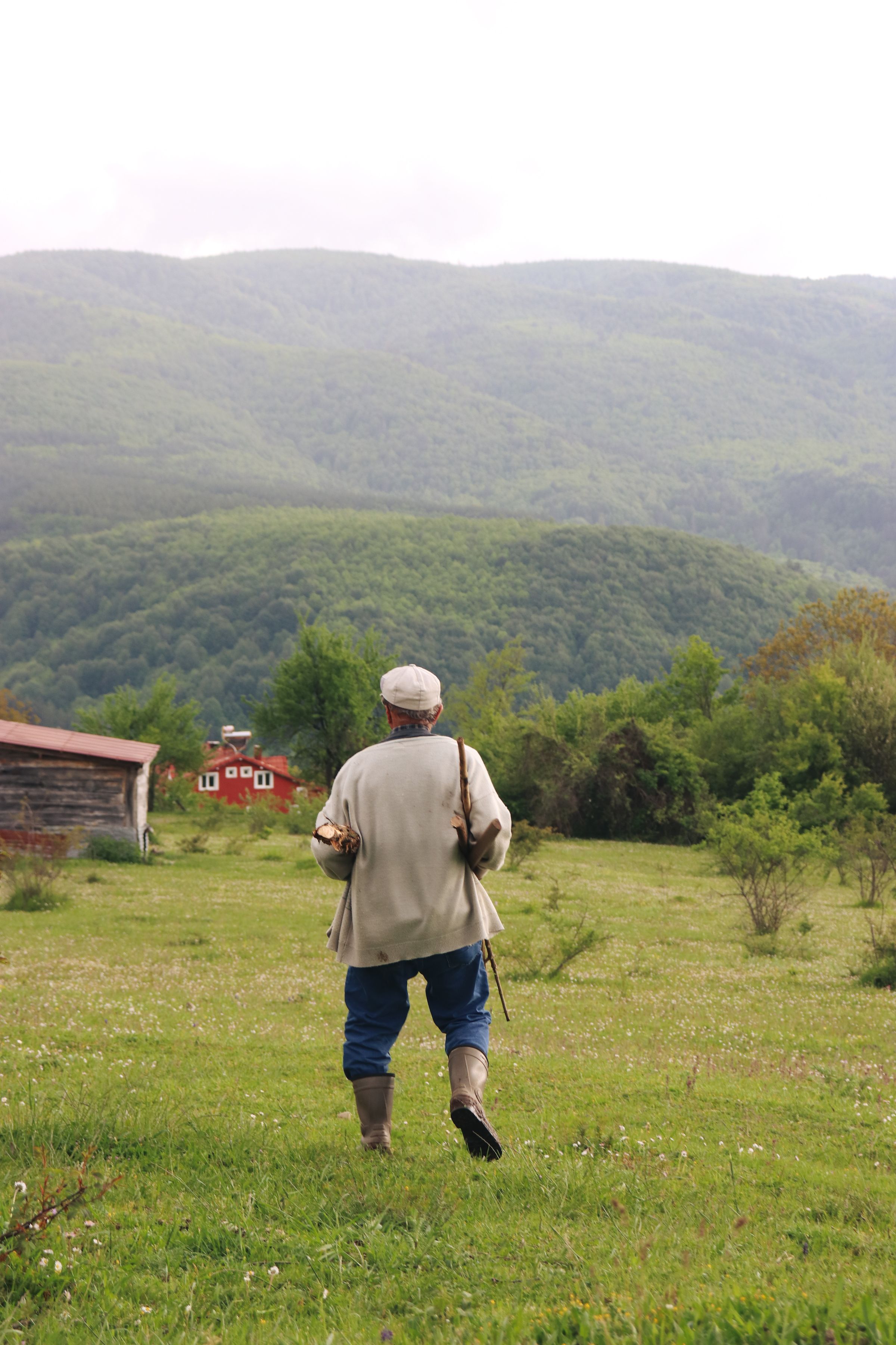 Productor caminando por la pradera, de espaldas, hacia los cerros